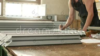 生产PVC窗户从型材，男工标记尺寸在PVC型材上，以进一步。